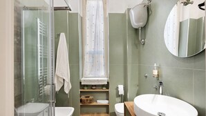 A bathroom with a glass shower enclosure, a white sink, a toilet, and a mirror. - Merliani House Holiday Home (Napoli)
