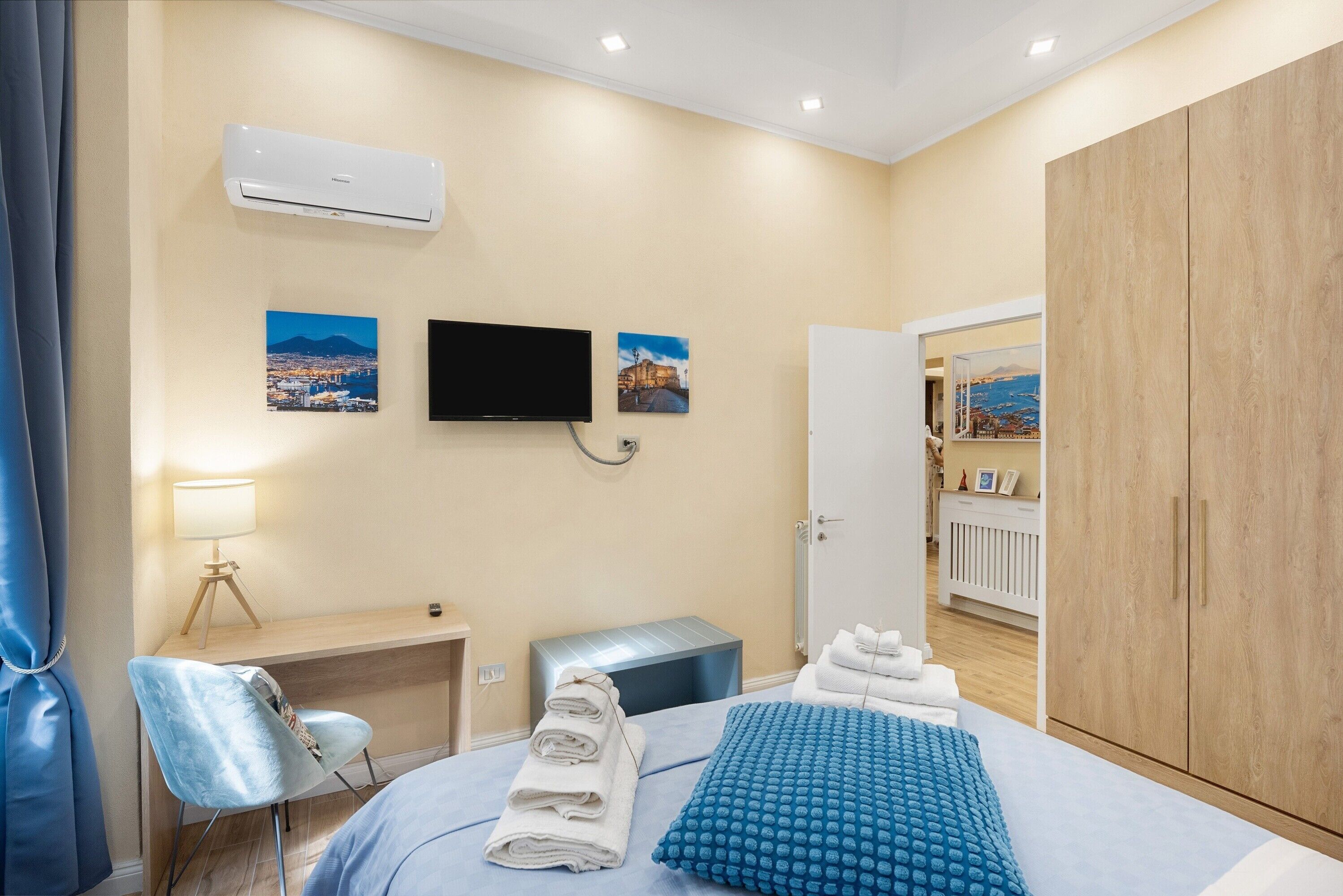 A hotel room with a bed, a desk, a chair, a TV, and a wardrobe.