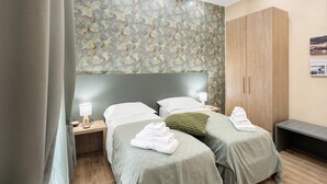 A hotel room with two beds, a wardrobe, and a wall with a leaf pattern. - Merliani House Holiday Home (Napoli)