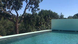Una piscina limpida con un albero e vegetazione sullo sfondo.
