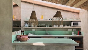 Una cucina con piano di lavoro in cemento, lampade decorative intrecciate a sospensione e un forno a microonde.