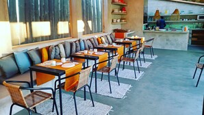 Un ristorante con un lungo tavolo comune, tavoli individuali e un'area bar.