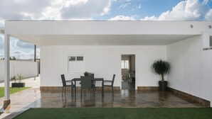A modern house with a patio, a dining table, chairs, and a potted plant.
