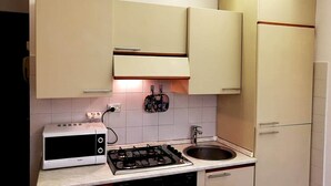 Eine Küche mit Herd, Mikrowelle, Spüle und Schränken.