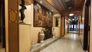 Un couloir doté d’un sol en marbre, de boiseries et de vases décoratifs.
