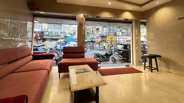 Un hall d’hôtel avec un canapé, une table et une vue sur la rue.