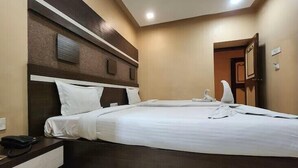 Une chambre d’hôtel avec un grand lit, une table de chevet avec un téléphone et une porte sur le côté droit.