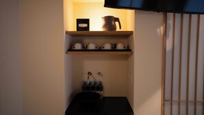 Una cocina compacta con un lavamanos negro, armarios de madera y un estante con utensilios de cocina.