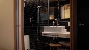 Un baño moderno con cabina de ducha de vidrio, un lavamanos blanco y un taburete de madera.