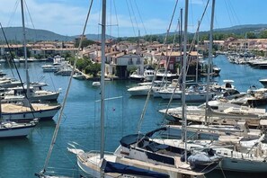 A marina with numerous boats docked, surrounded by buildings and hills in the background.