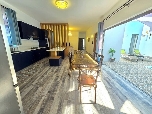 Una cocina moderna con armarios oscuros, una mesa de comedor de madera y vistas al área de estar exterior.