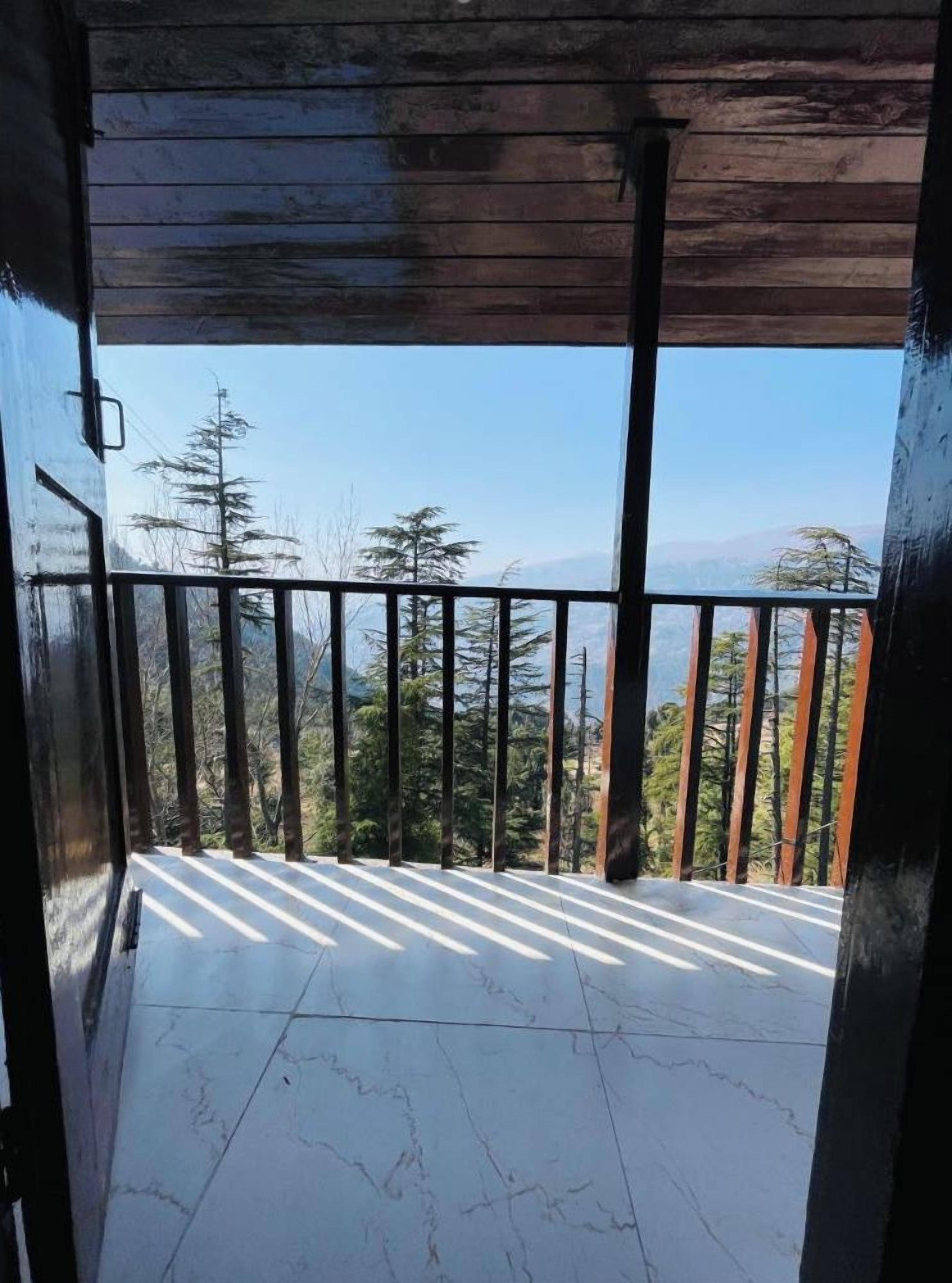 Un balcone con vista su alberi e montagne.