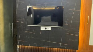 Quarto moderno com uma grande televisão de tela plana fixada em uma parede de mármore preto.