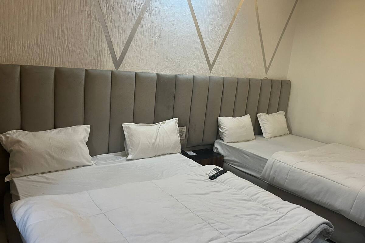 A hotel room with two beds, a headboard, and a wall with a geometric pattern.