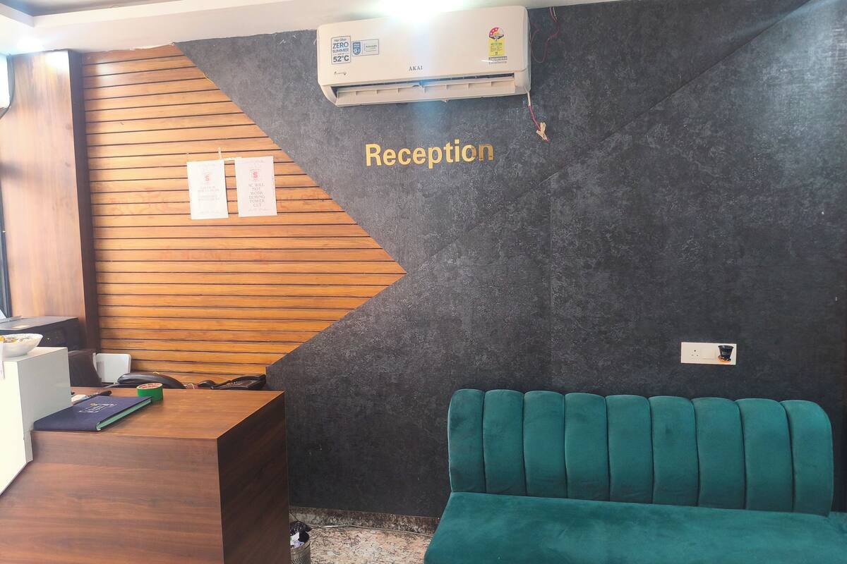 A reception area with a wooden desk, a teal sofa, and a wall-mounted air conditioner.