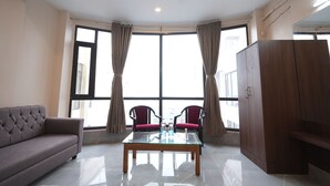 Une chambre moderne comprenant un canapé, deux fauteuils, une table avec un plateau en verre et une armoire.