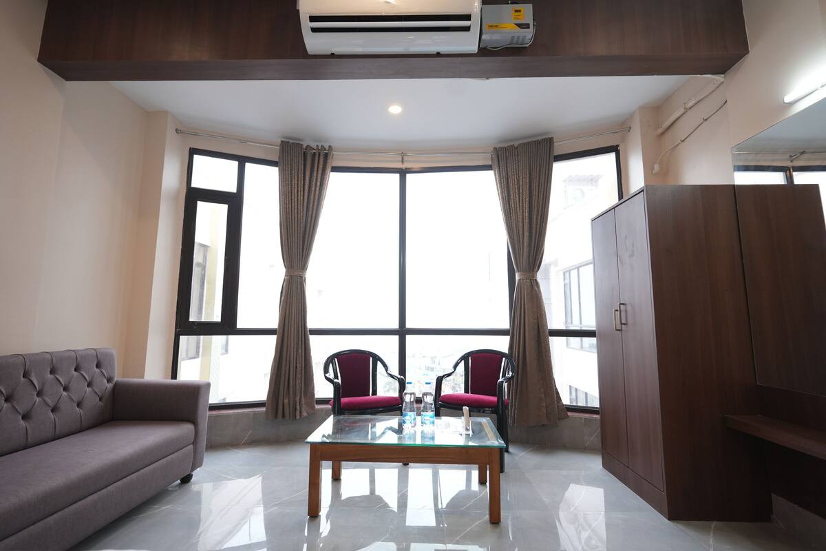 A modern room with a sofa, two chairs, a glass-top table, and a wardrobe.