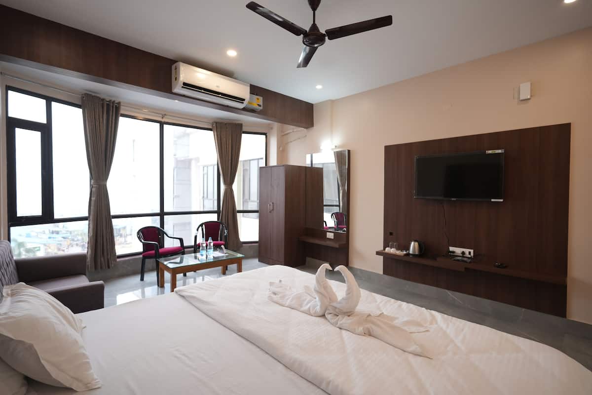 A hotel room with a bed, a desk, a chair, a television, and a window with curtains.