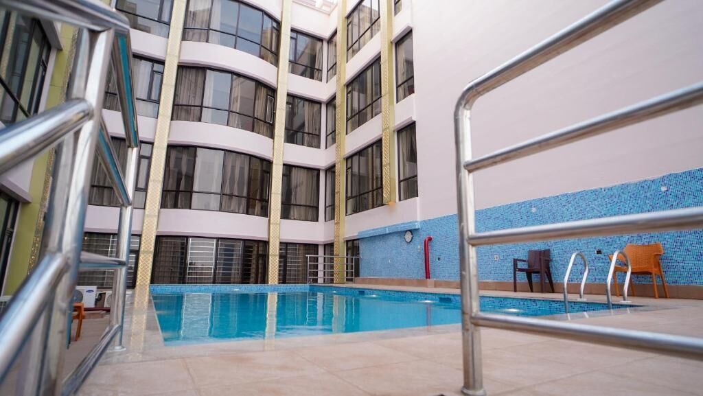 An indoor swimming pool with a view of a multi-story building with balconies.