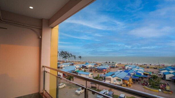 Un balcon donnant sur une zone commerçante située en bord de mer, avec des étals et un ciel dégagé.