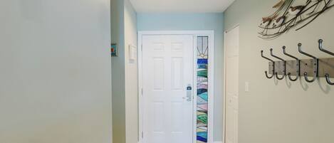 A hallway with a white door, a wall-mounted coat rack, and a patterned rug.