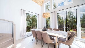 A modern dining area with a large table, six chairs, and a hanging light fixture. - Spa and Pool Table | Chalet Ayoka (Shannon)