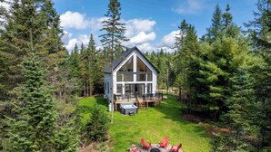 A modern house with a deck, surrounded by dense forest. - Spa and Pool Table | Chalet Ayoka (Shannon)