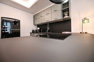 Una cocina moderna con horno empotrado, cafetera y pileta.