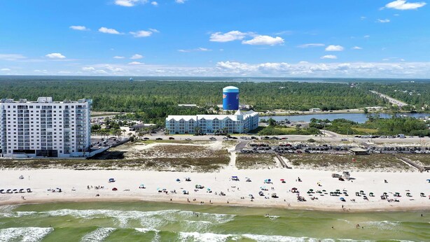 Een hotel aan de kust met uitzicht op het strand, een grote watertoren en een parkeerplaats.