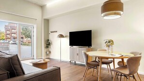 Een moderne woonkamer met een eethoek, een flatscreen televisie en een groot raam.