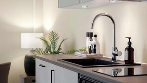 Een moderne keuken met een rvs spoelbak, een kraan en een zeepdispenser.