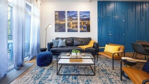 Un moderno salón con un sofá de cuero negro, una mesa de centro y una pared decorativa azul.
