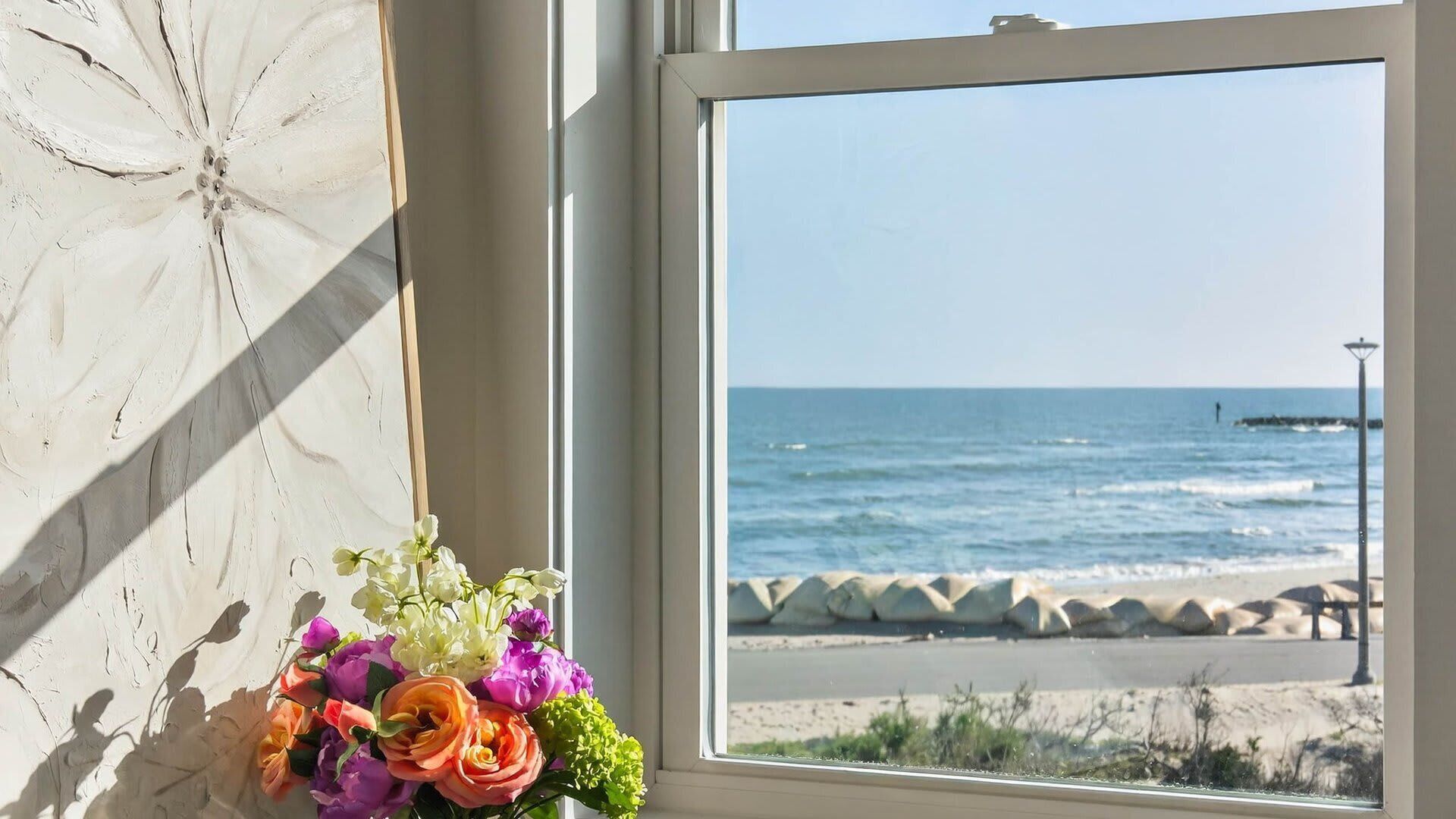 Uma janela com vista para o oceano e a praia.
