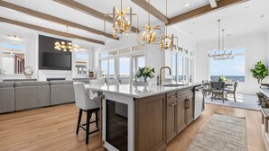 A modern kitchen with a large island, built-in appliances, and a view of the ocean.