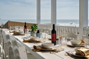 A table set for dining with a view of the ocean, white chairs, and a bottle of wine. - Oceanfront Pool & Spa, Volleyball Court, Game Rm (Corolla)