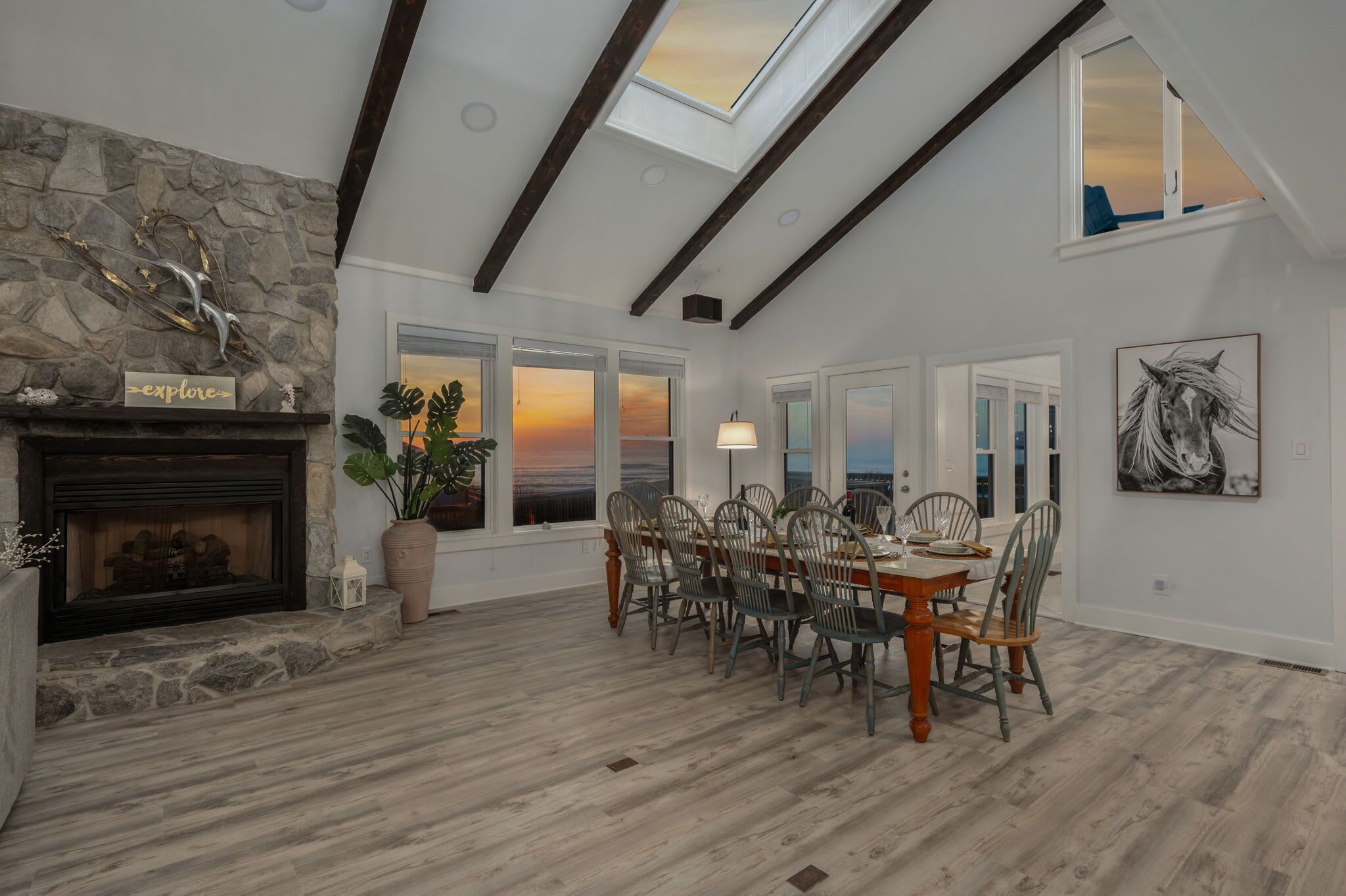 Comedor con chimenea de piedra, ventanas amplias y tragaluces.