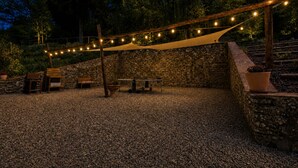 An outdoor patio area with stone walls, wooden furniture, and string lights. - Private Tuscan farmhouse with infinity pool, panoramic view with 14 seats (Pelago)