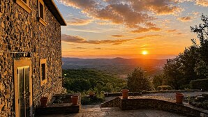 A stone building with a view of the sunset over a hilly landscape. - Private Tuscan farmhouse with infinity pool, panoramic view with 14 seats (Pelago)