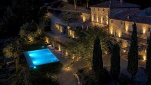 A stone building with a swimming pool, surrounded by trees and a well-lit pathway. - Private Tuscan farmhouse with an infinity pool and panoramic views, sleeps 16 (Pelago)