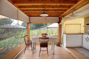 Eine Holzterrasse mit Tisch und Stühlen, einer hängenden Lampe und Blick auf einen Garten.