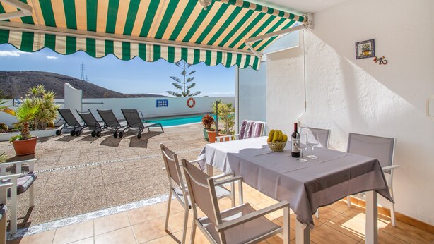Eine Terrasse mit Tisch, Stühlen, einem Pool und Blick auf die Landschaft.