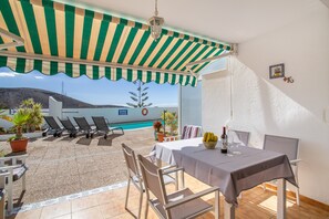 Une terrasse avec une table, des chaises, une piscine et une vue sur le paysage.