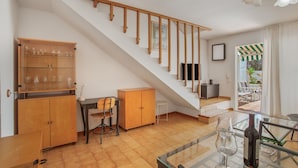 Ein modernes Interieur mit Treppe, Holzschränken, einem Esstisch und einem Glastisch mit einer Weinflasche.