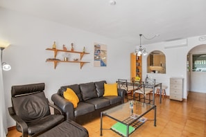 A modern living room with a leather sofa, glass coffee table, and wooden shelves. - Vacation Home 'Carmelo' with Shared Pool, Wi-Fi and Air Conditioning (Mogán. Arguineguín)