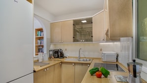 Eine kleine Küche mit Kühlschrank, Mikrowelle, Spüle und Kaffeemaschine.