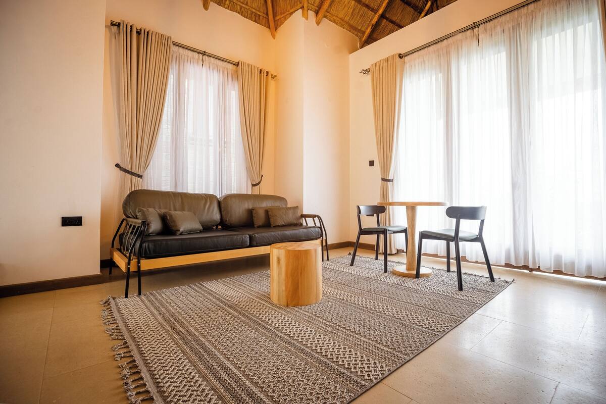 A modern living room with a sofa, a round wooden coffee table, and a dining area with a table and chairs.