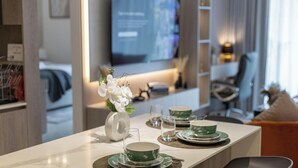 A modern dining area with a marble countertop, green and white tableware, and a vase with white flowers. - Manzil- Chic 2BR w Pool nr Circle Mall  (Dubai)