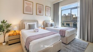 A hotel room with two beds, a potted plant, and artwork on the wall. - Manzil- Chic 2BR w Pool nr Circle Mall  (Dubai)