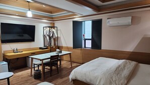 A hotel room with a bed, a desk with a chair, a TV, and a window with blinds. - Central Plaza Hotel (Suwon)