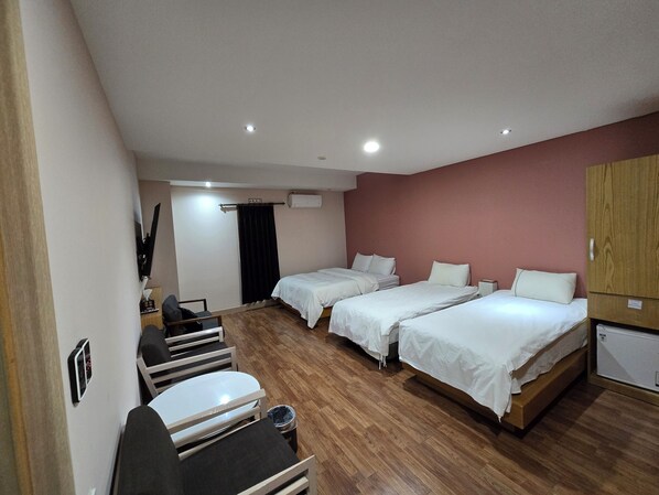Una habitación de hotel con dos camas, un escritorio, una silla, suelo de madera y un armario.
